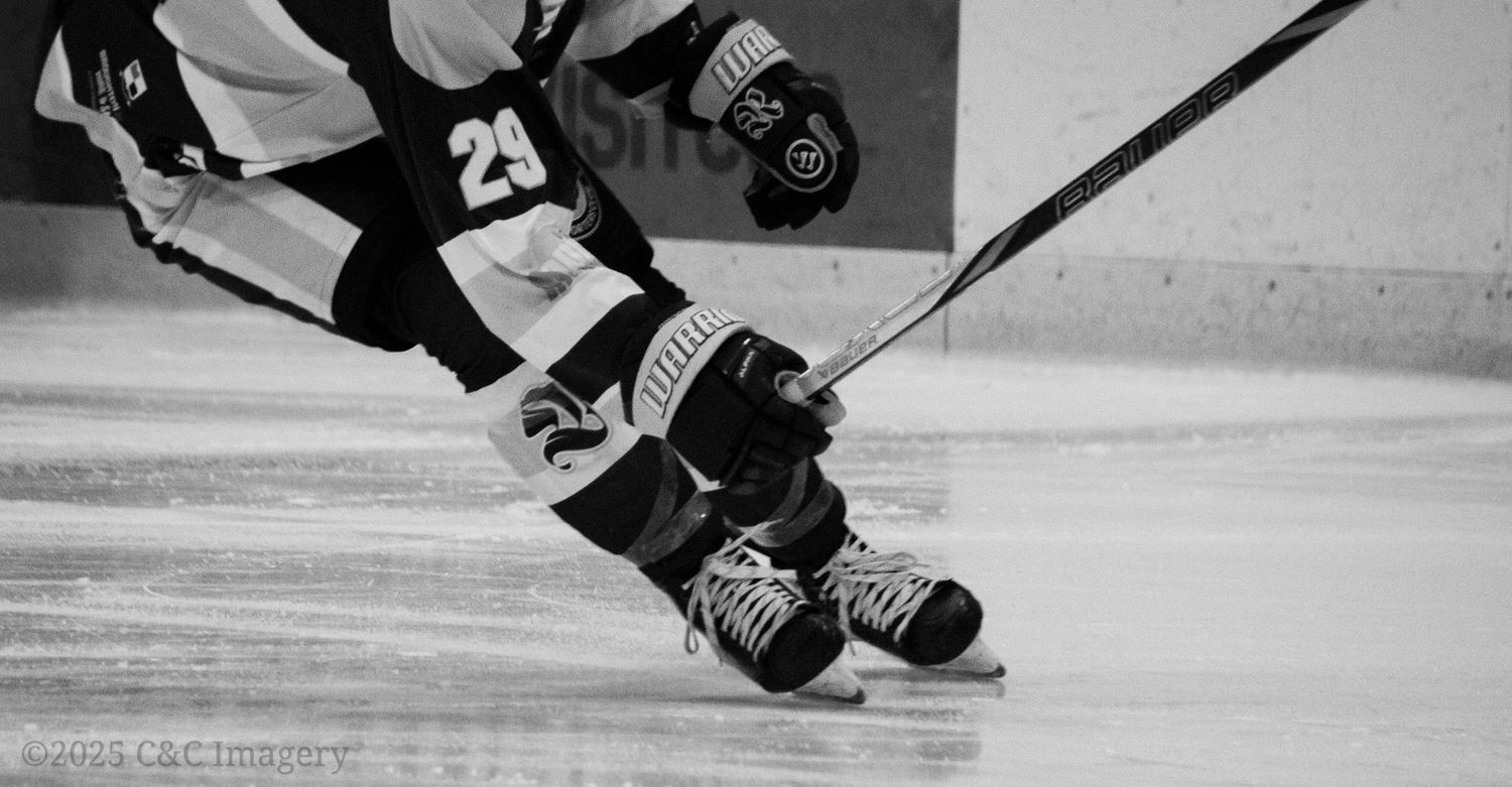 Close-up view of hockey players' skates and sticks on ice during intense gameplay action.