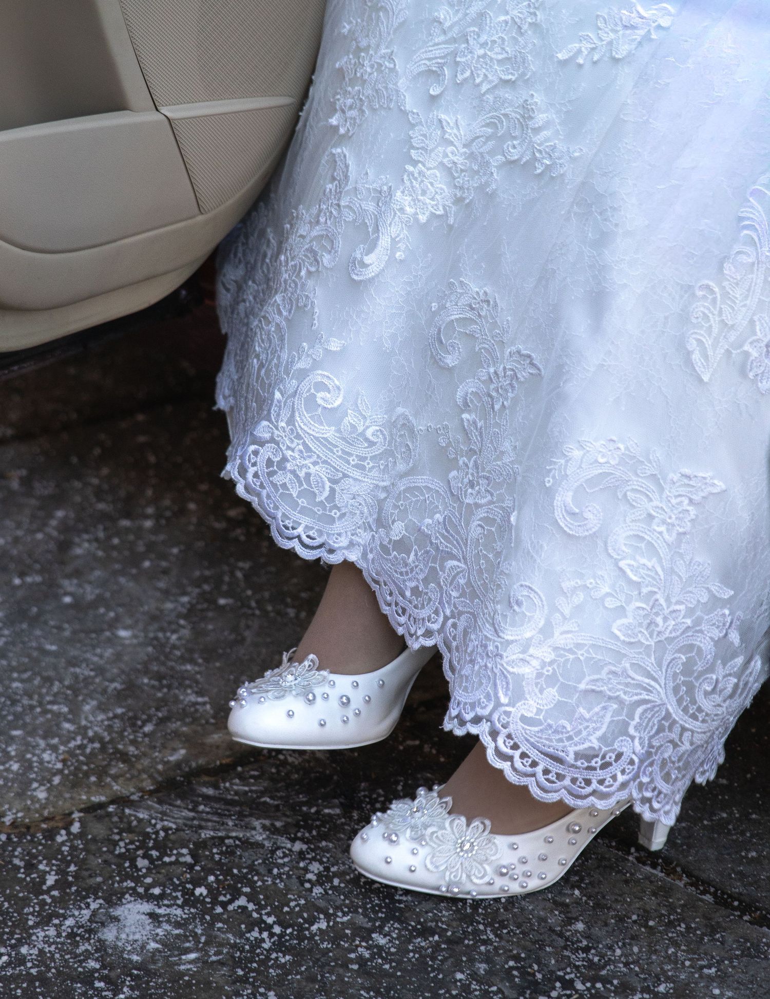 Close-up sequence showing white lace wedding dress hem and bridal shoes on textured ground.