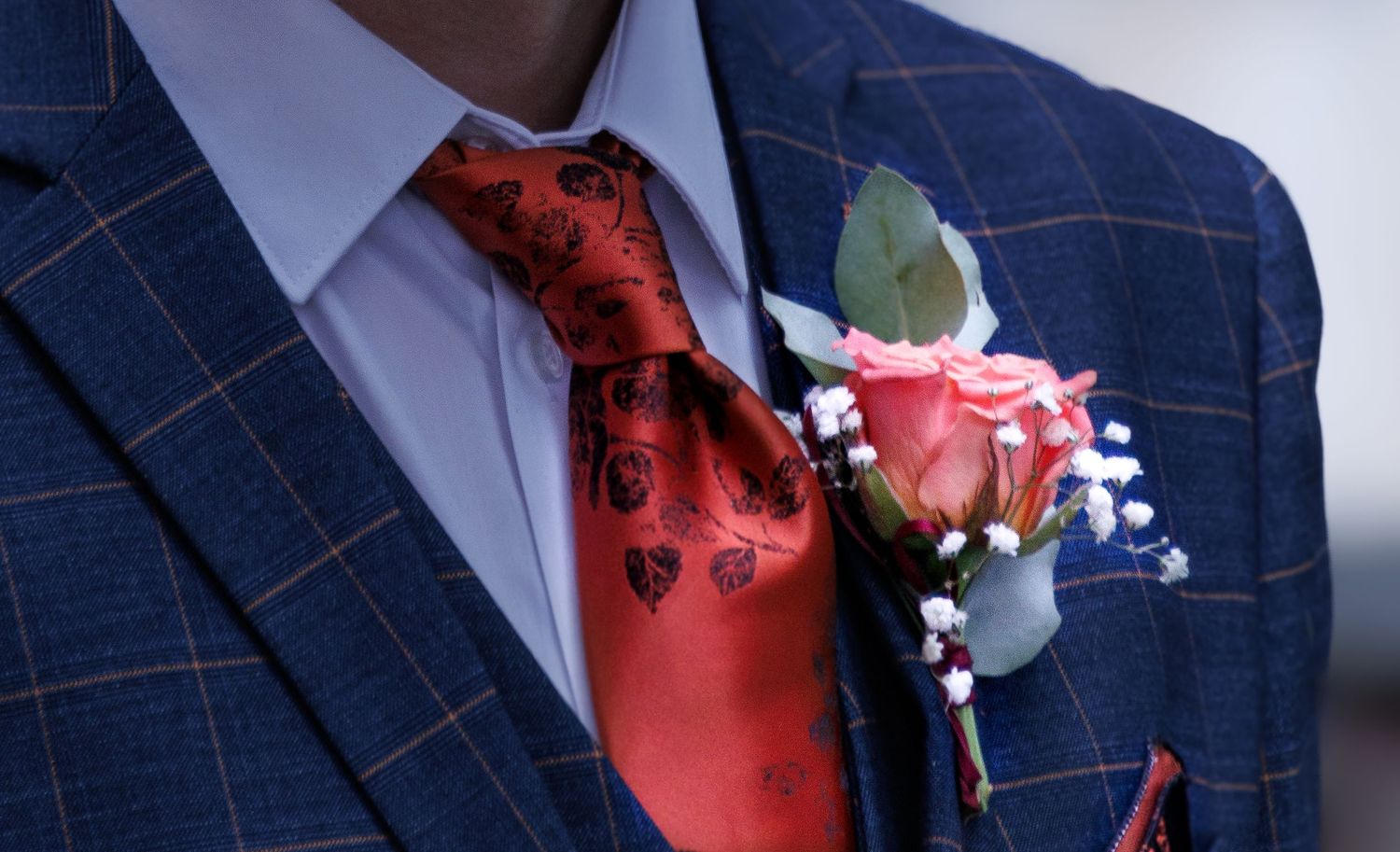 Close-up details of a navy blue plaid suit jacket with red accents.