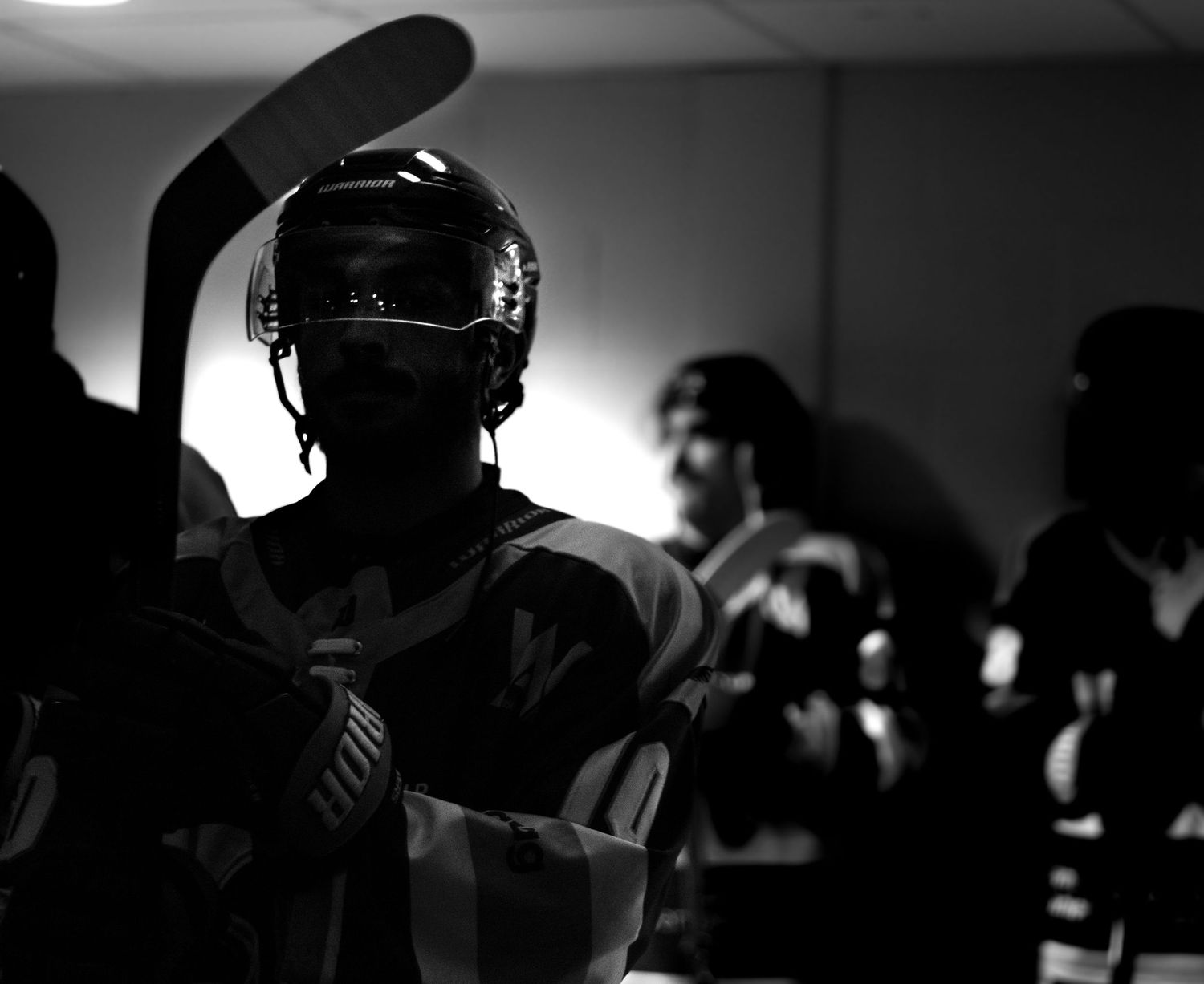 A dramatic black and white montage of hockey players in action with silhouettes and helmets visible.