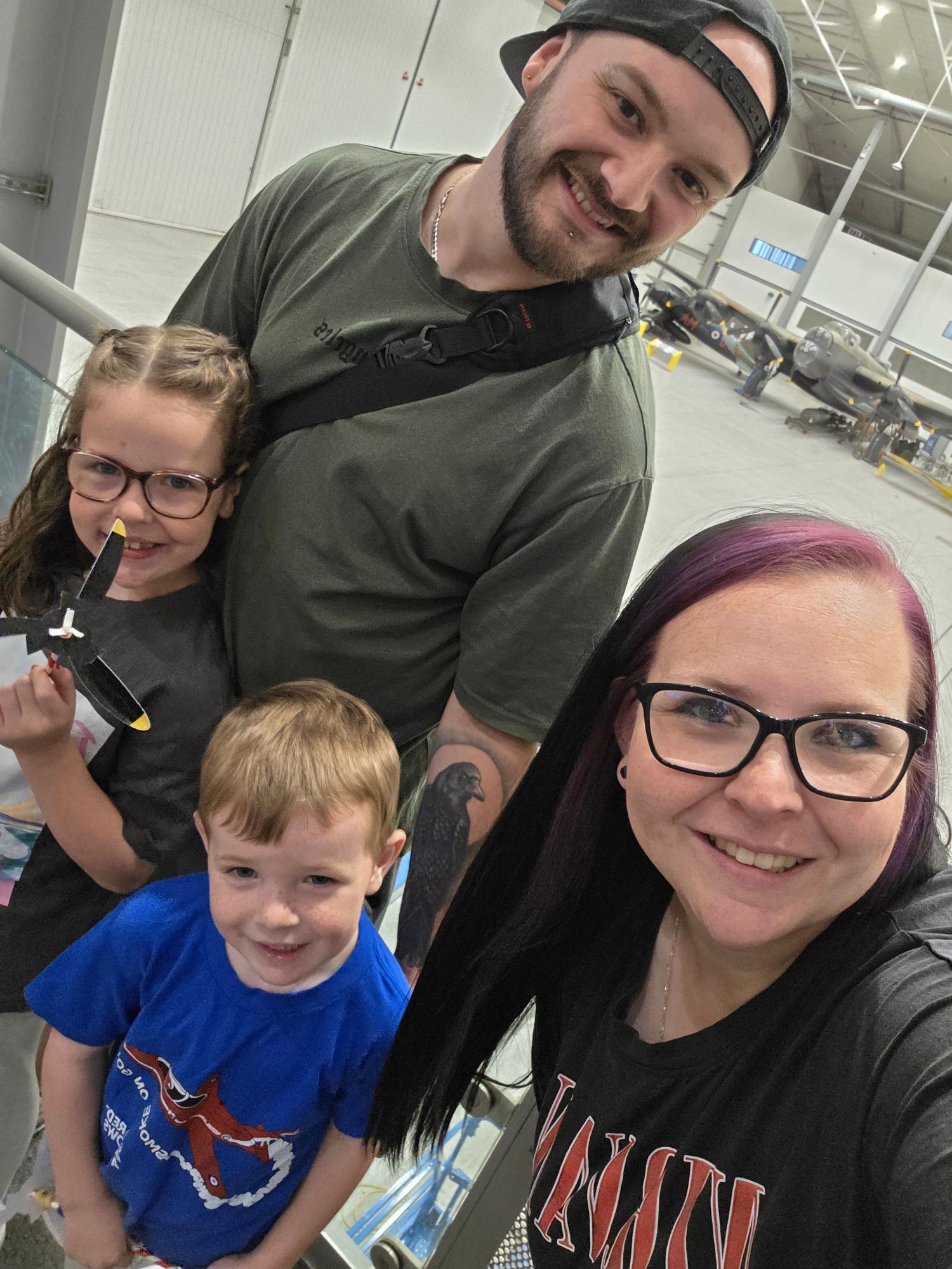 A family takes a selfie together in what appears to be a bright indoor space.