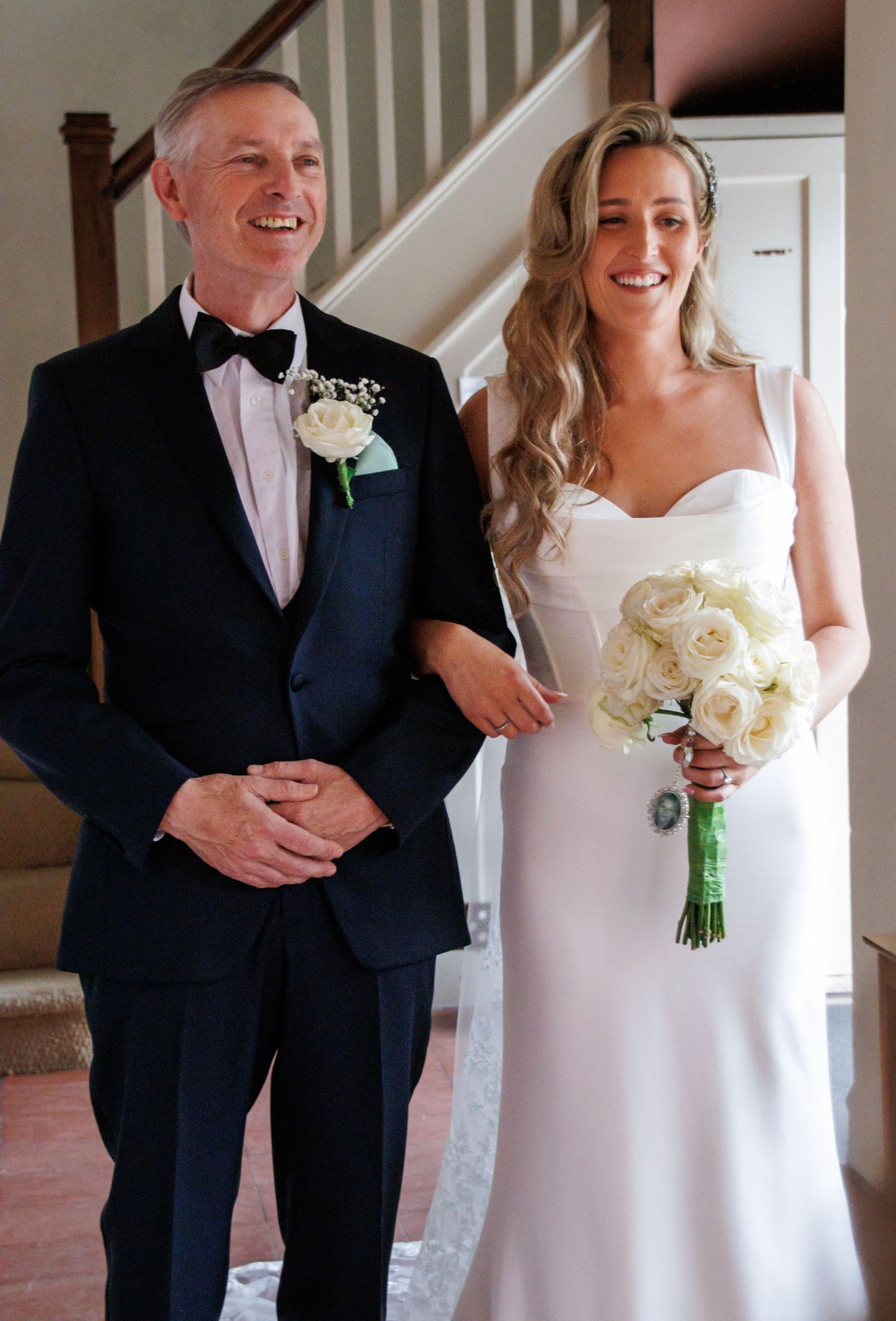 Wedding party standing together in formal attire with white bouquet.