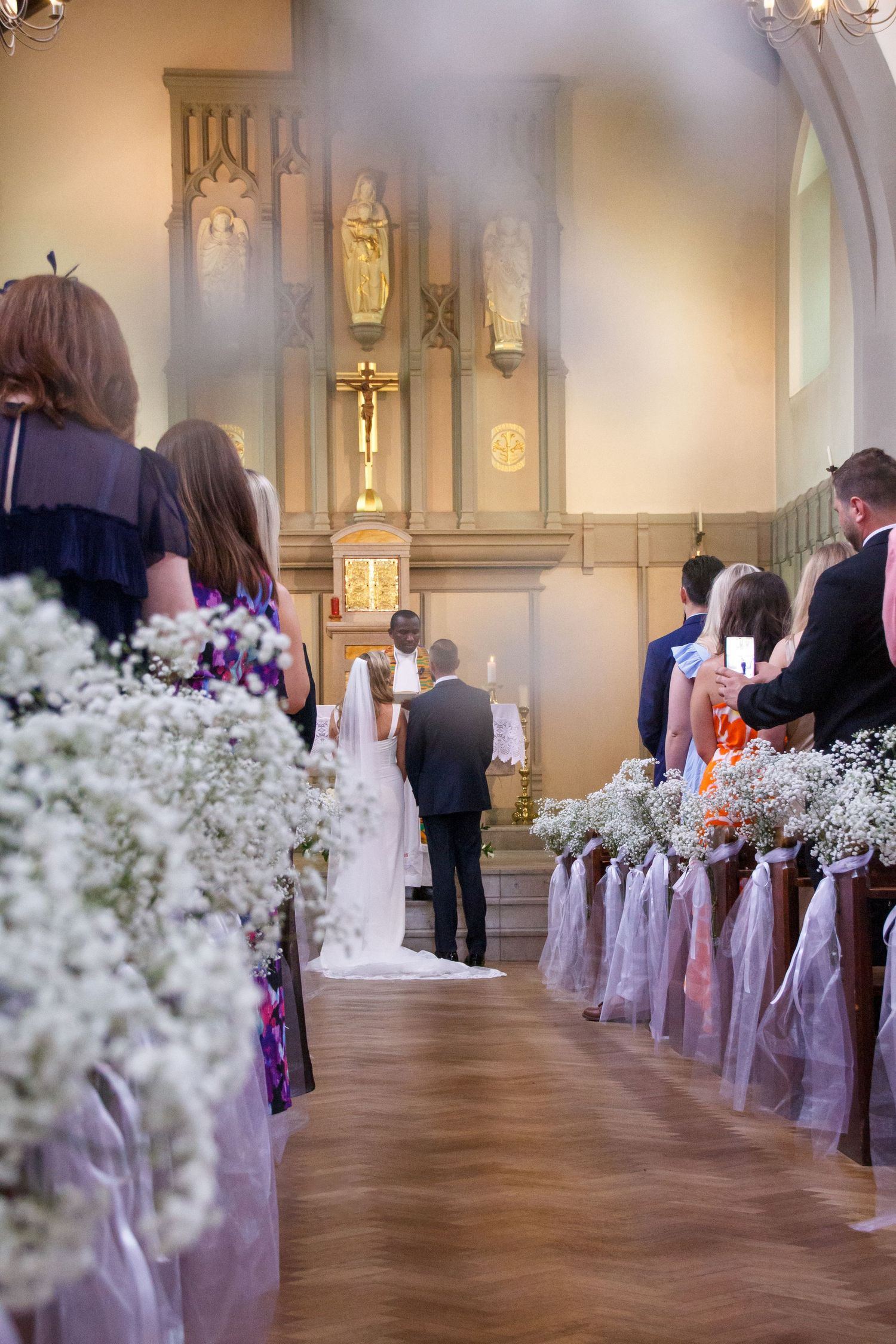Church wedding ceremony aisle decorated with baby's breath and purple ribbons.