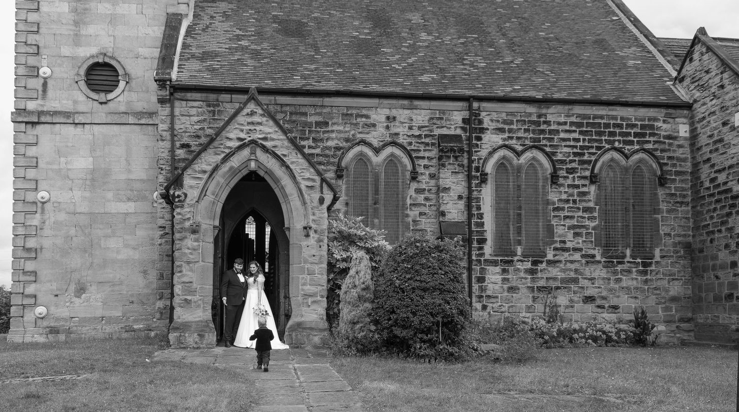 Bride and groom standing outside a historic stone church entrance on their wedding day.