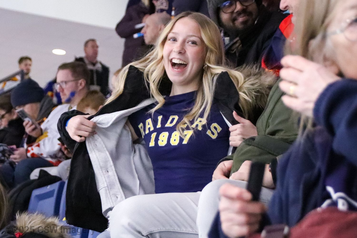Enthusiastic sports fans cheer and celebrate in stadium seating.