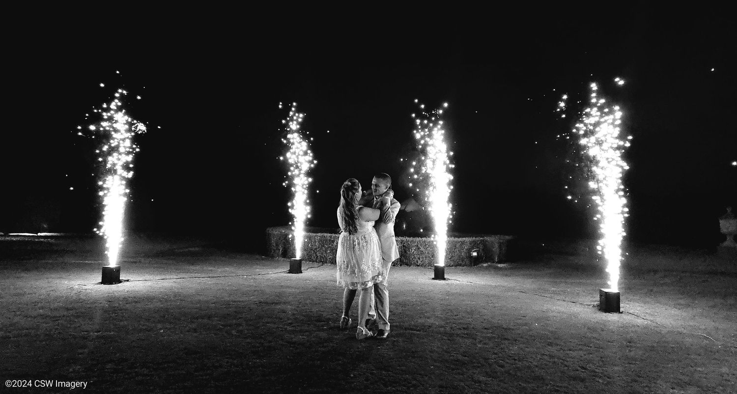 Dramatic black and white photos of sparkler fountains illuminating a nighttime wedding celebration.