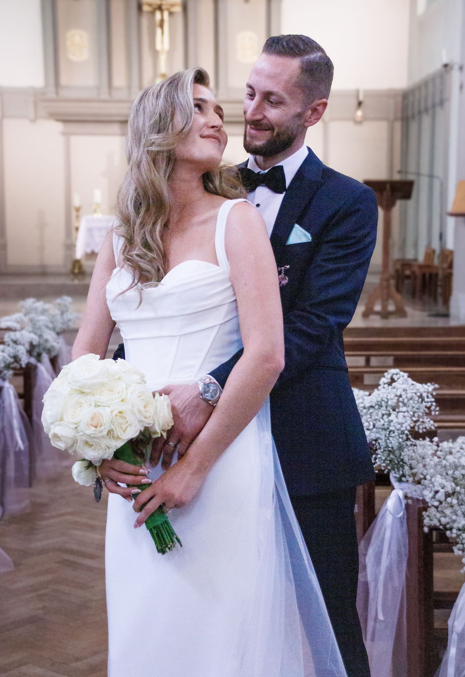 Romantic wedding moments captured inside an elegant church with white floral decorations.