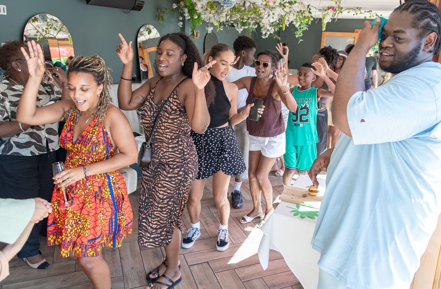 Diverse group of people dancing and celebrating together at an outdoor party event in summer attire.