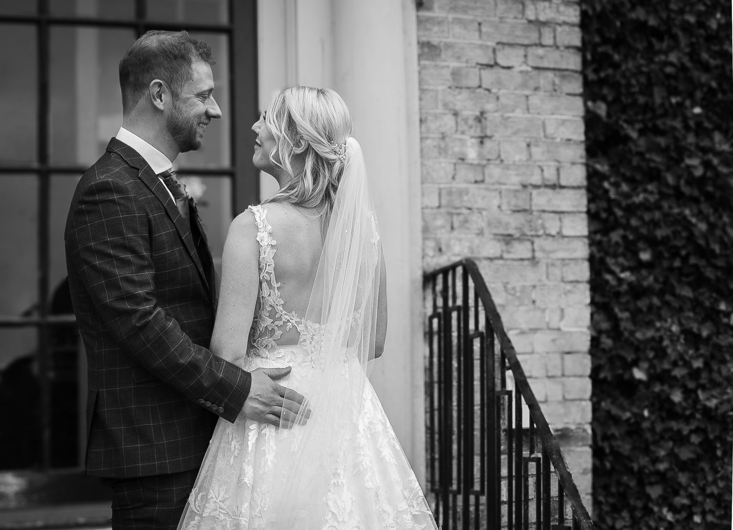 A sequence of romantic wedding moments captured in black and white outside a historic building.