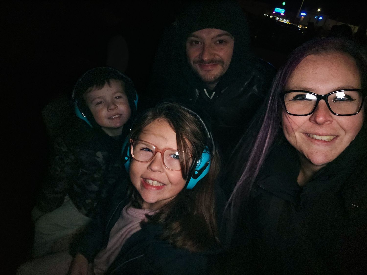 A family taking a nighttime selfie with blue headphones visible.