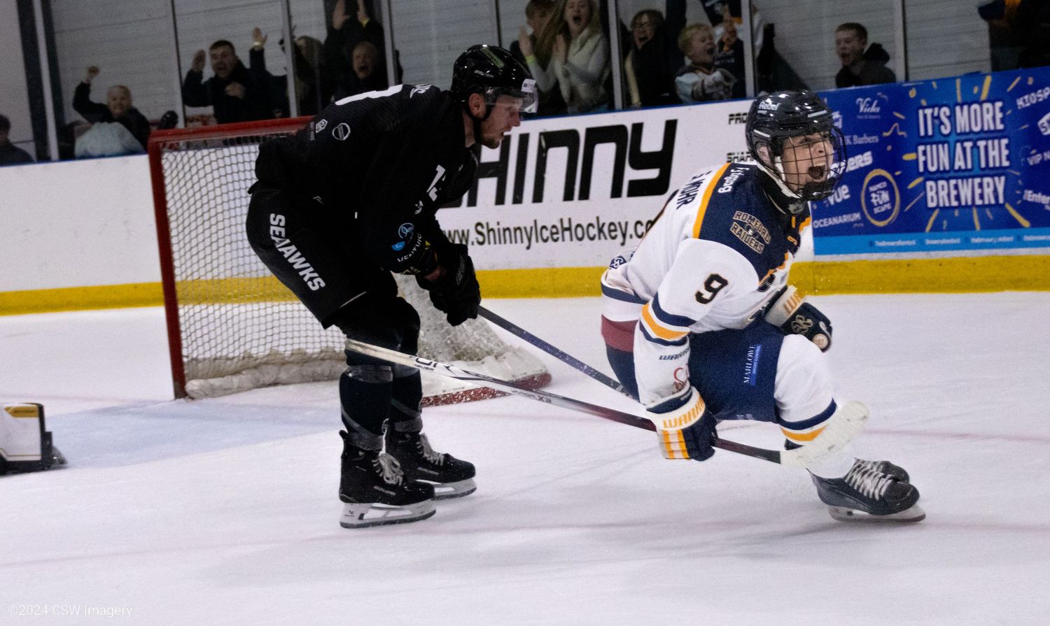 Hockey players in action on the ice with one player sliding across the rink.