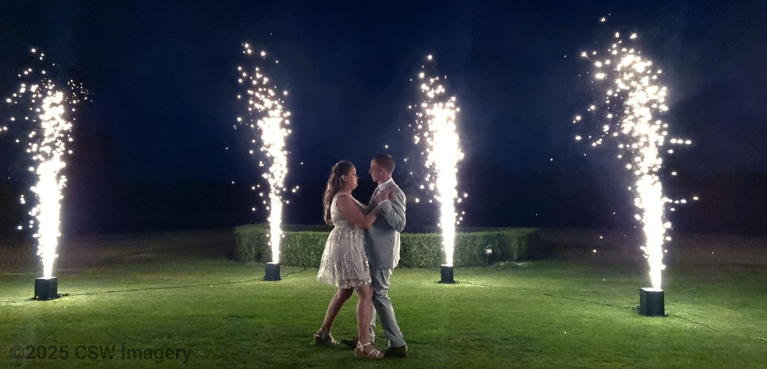 Outdoor nighttime wedding scene with bright white sparkler fountains creating a magical atmosphere.