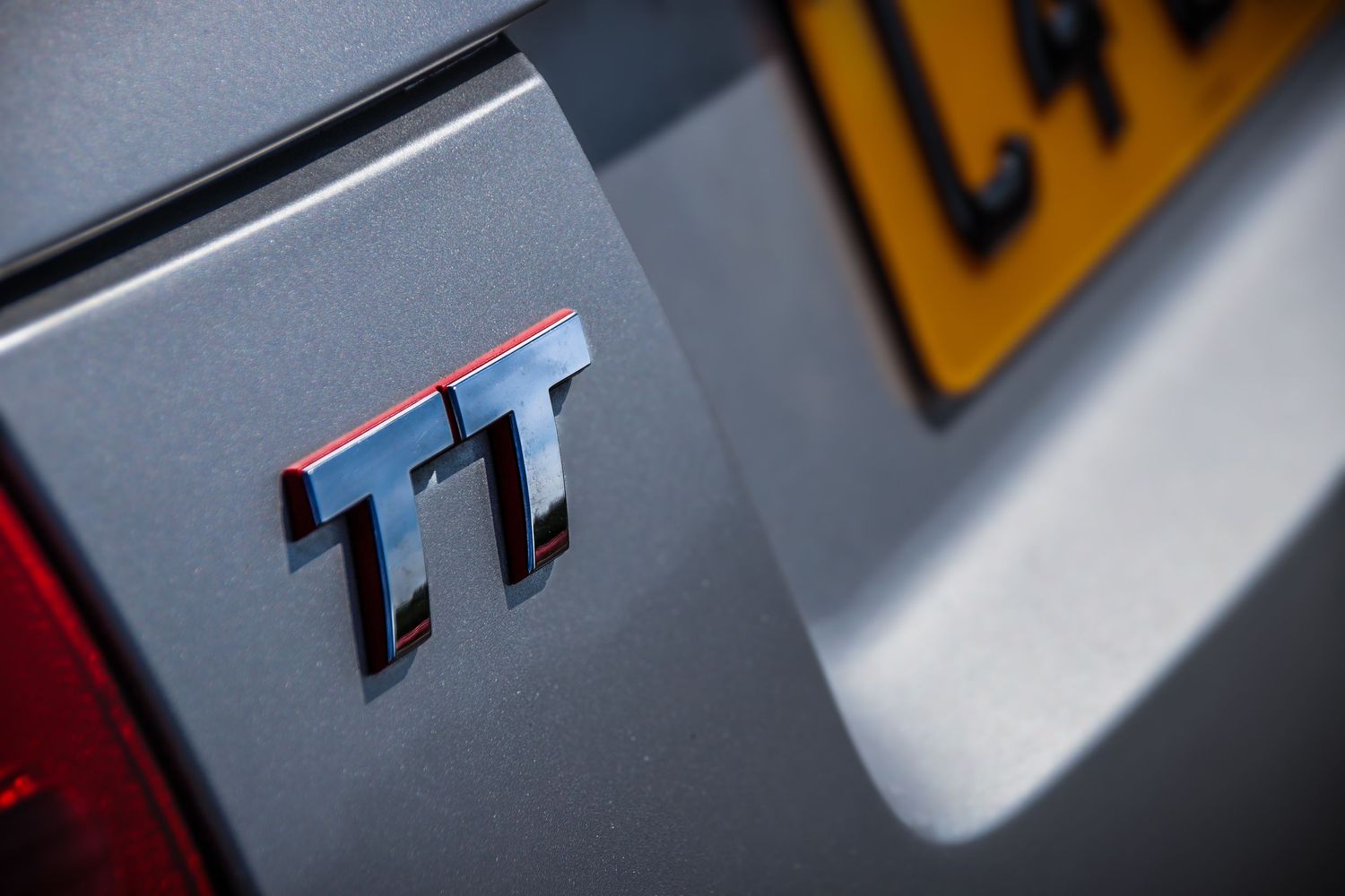 Close-up macro shots of a silver car emblem or badge showing reflective metallic details and shadows.