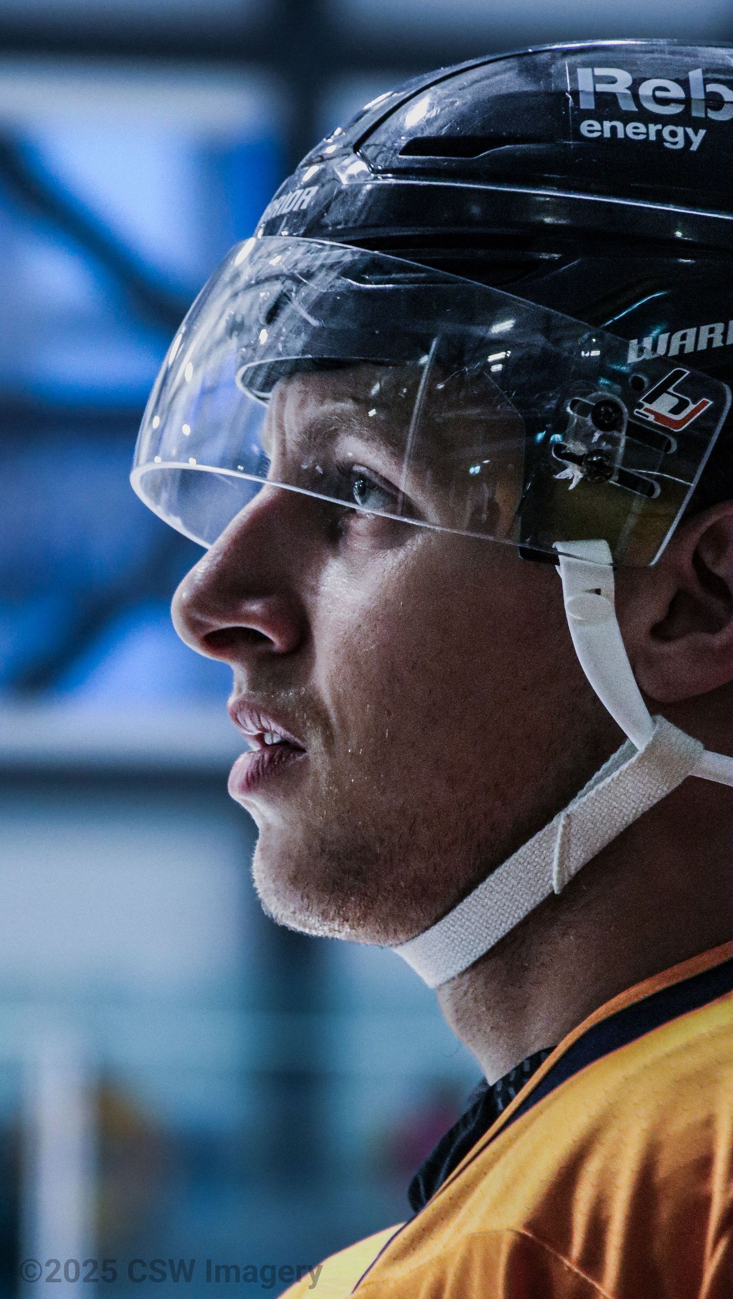 Hockey player in yellow jersey shown in profile view wearing helmet with visor.