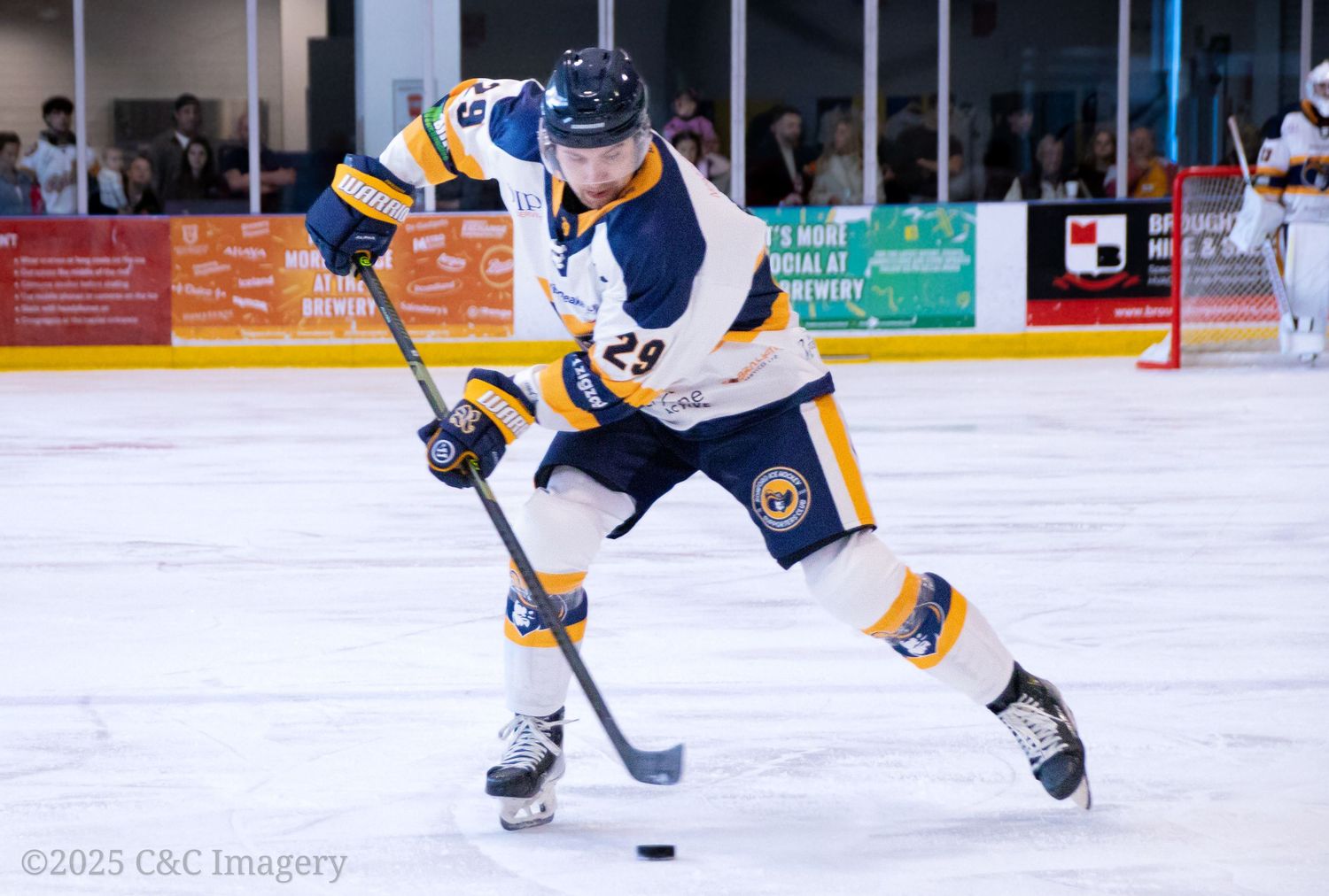 Hockey player in motion handles puck while skating in navy and white uniform.
