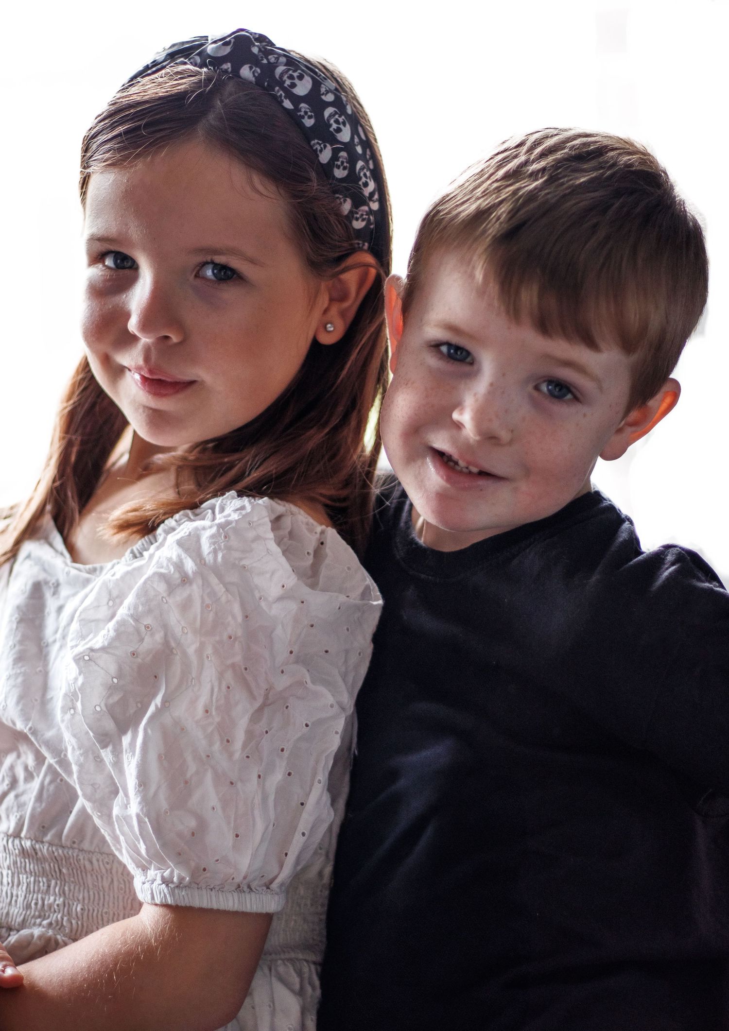 Portrait of children in formal attire against white background.