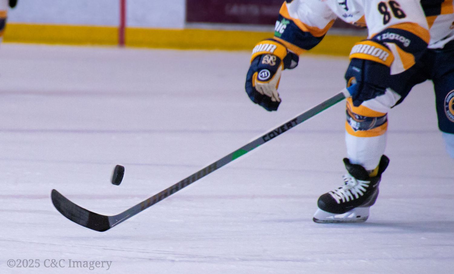 Close up of hockey stick and puck on ice during game action.