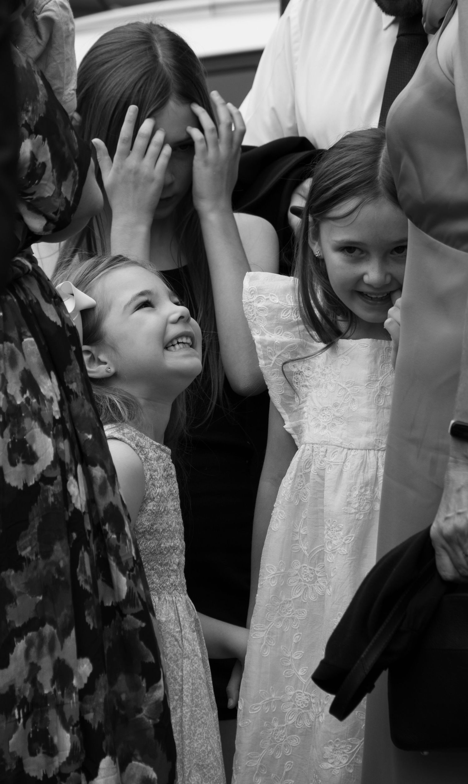 Black and white photo of young flower girls in white dresses at a wedding.