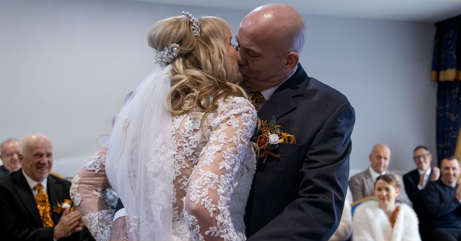 Couple dancing at a wedding reception with guests watching in the background.