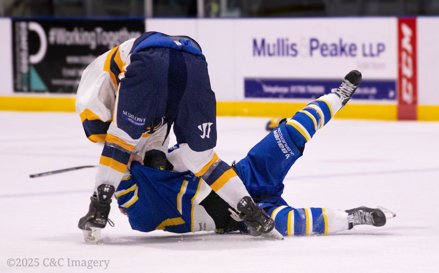 Two hockey players collide and fall on ice during intense game action.