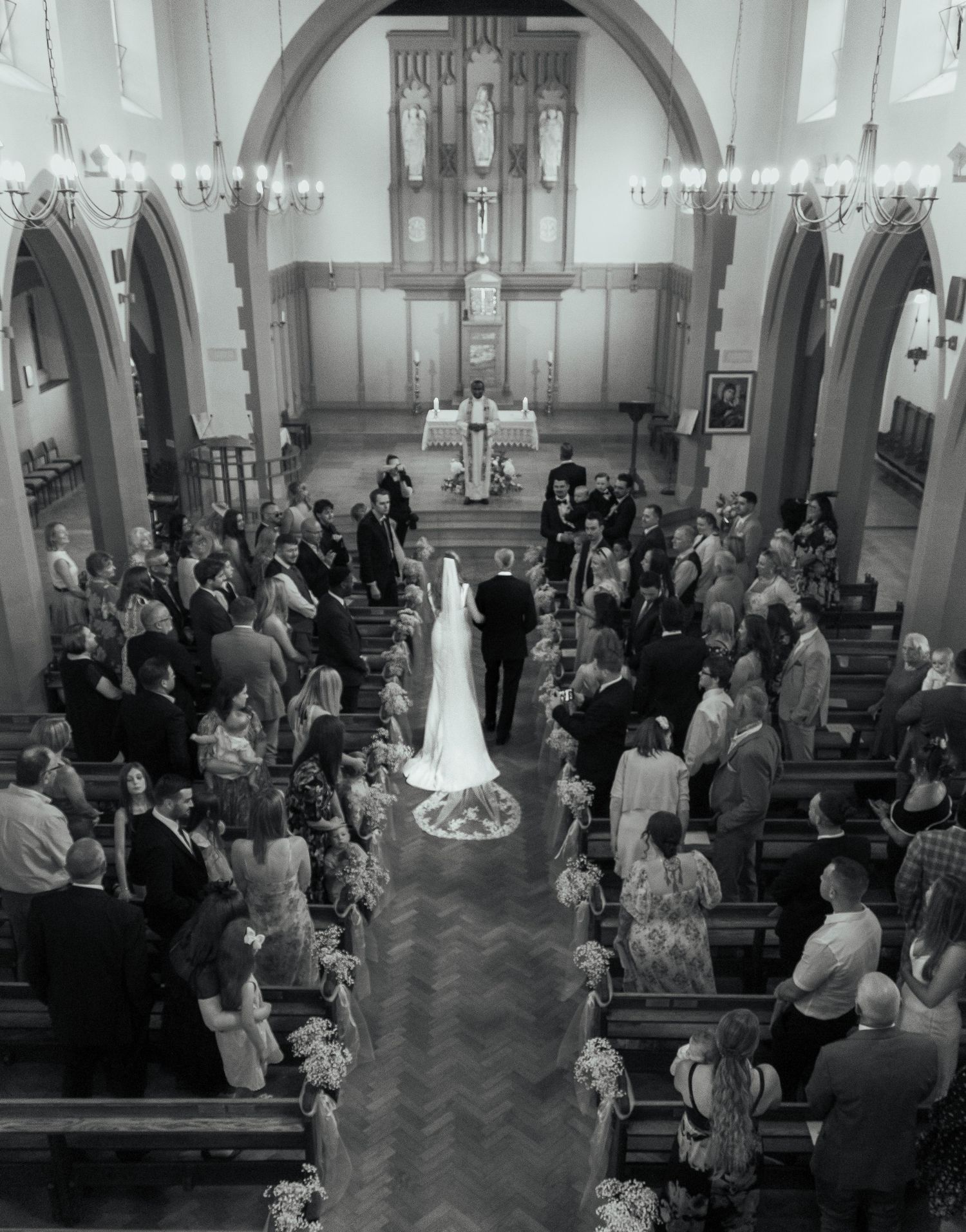 Black and white aerial view of wedding ceremony in progress inside traditional church.