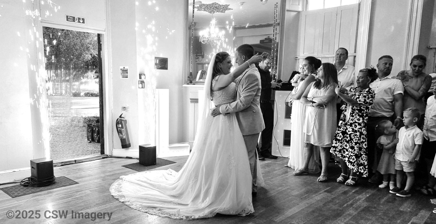 Wedding reception venue with sparkling lights and guests celebrating in a bright indoor space.