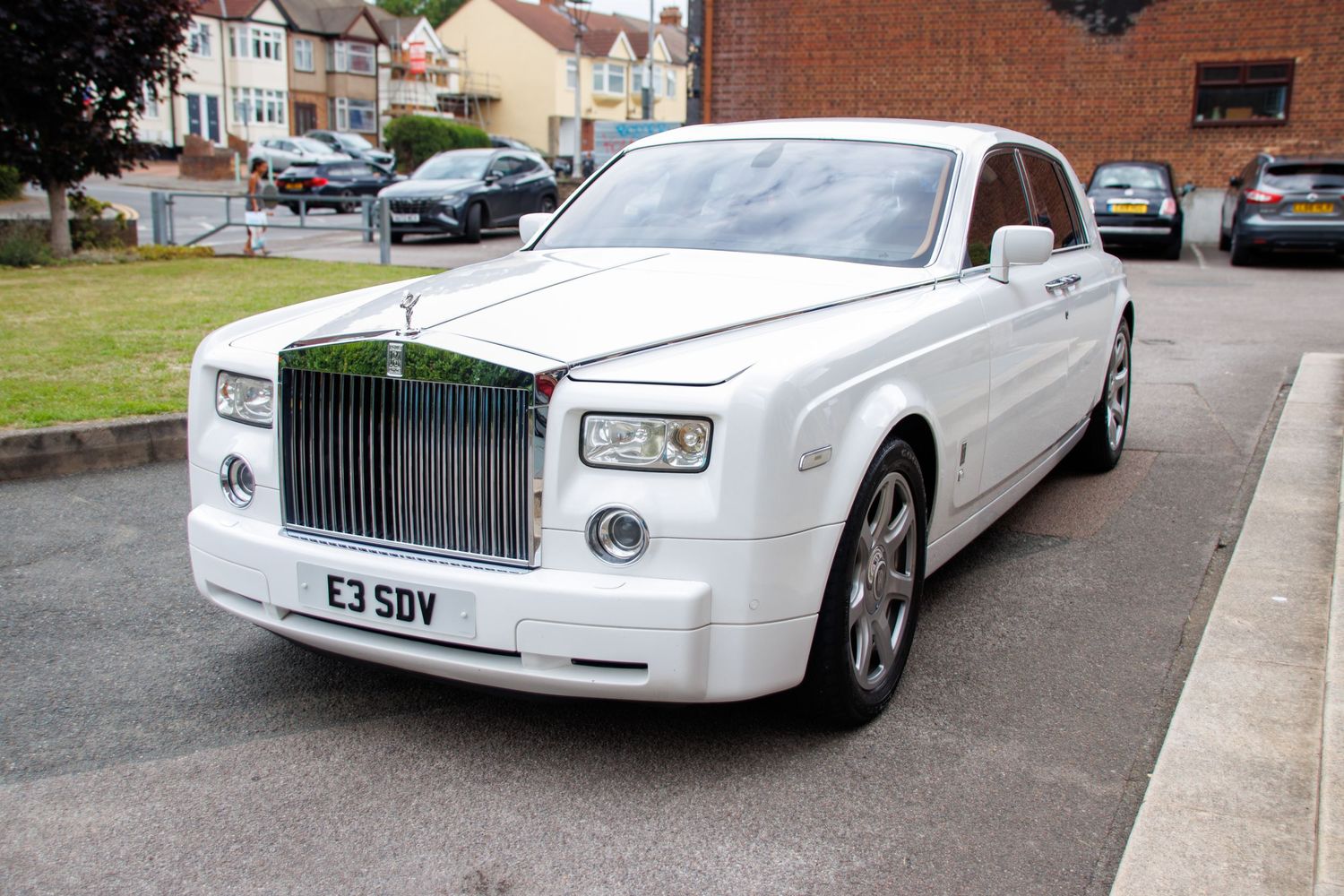 Line of white luxury Rolls Royce vehicles parked on residential street.