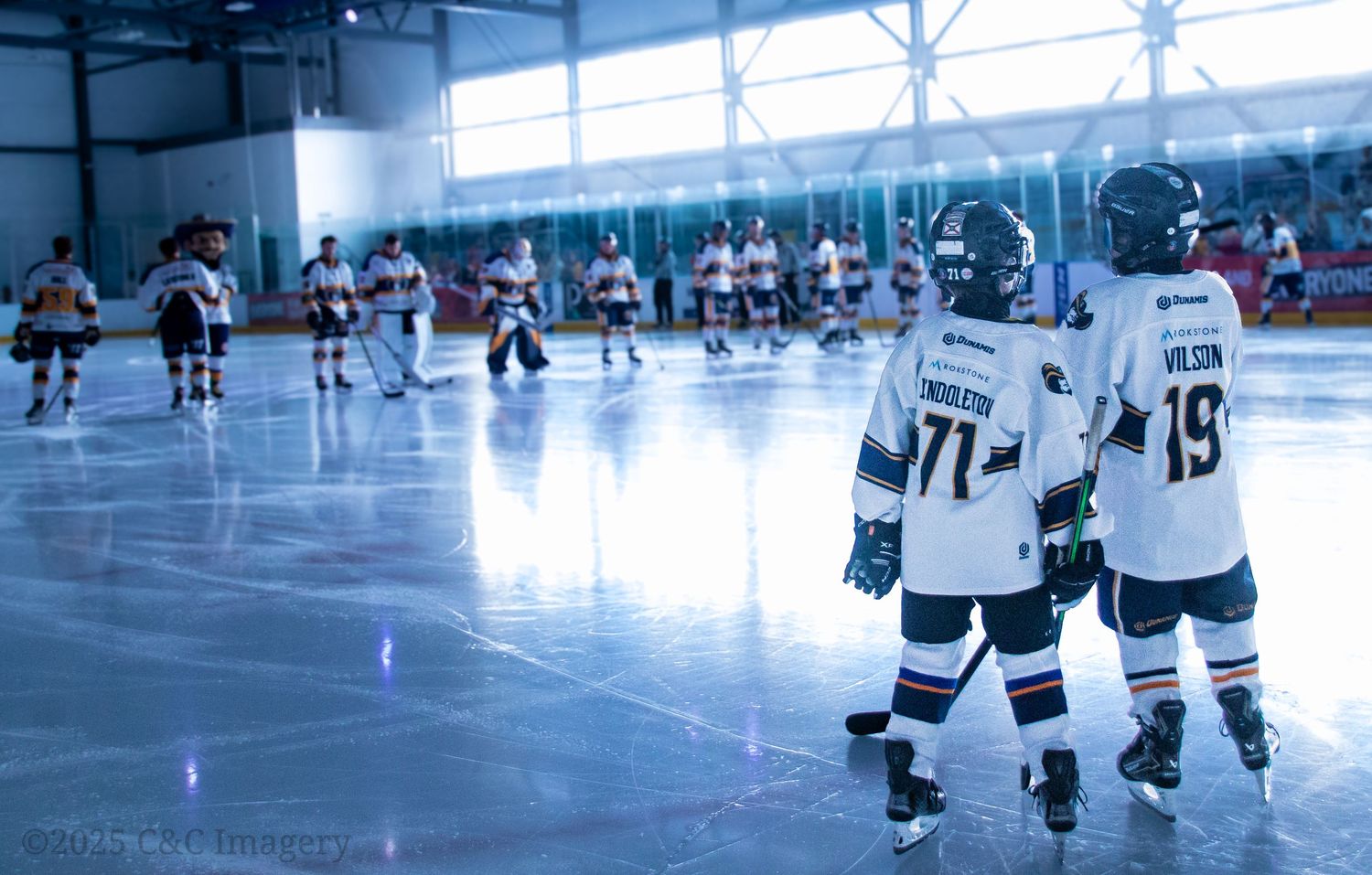 Two hockey players skate together on ice rink during practice or game.
