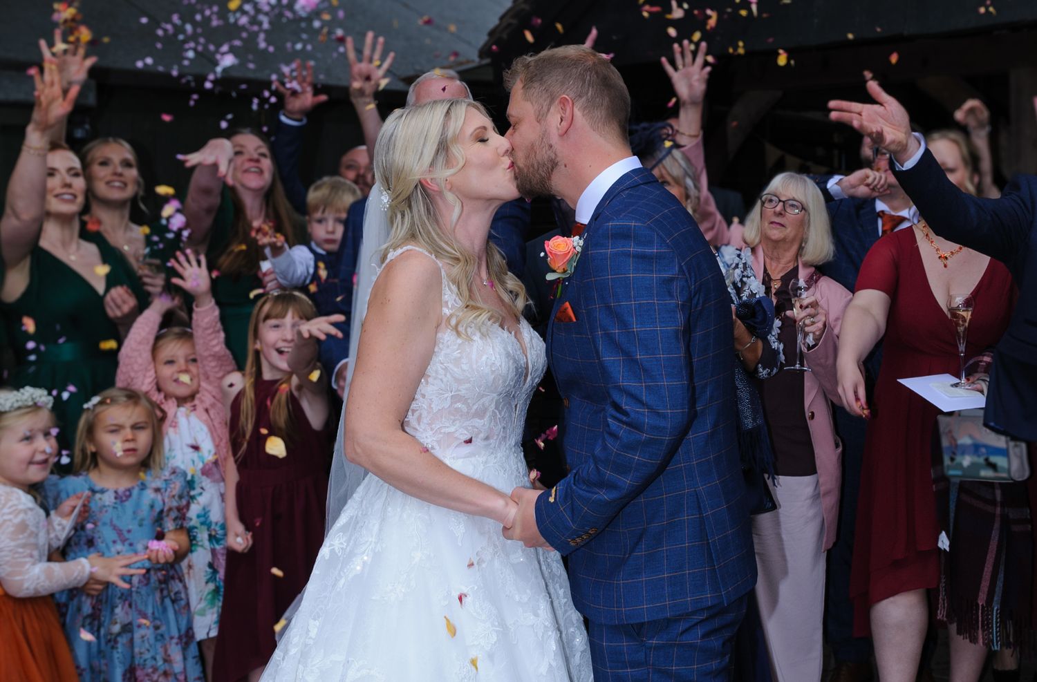 Wedding guests celebrate on dance floor with confetti while couple shares romantic dance in elegant reception venue.