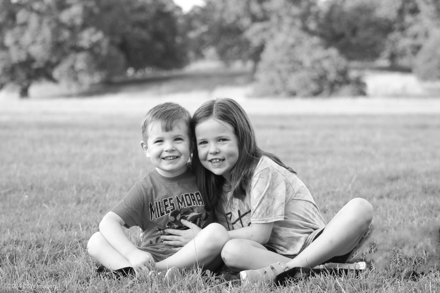 Black and white photo of people lying in grass during a casual outdoor photoshoot.