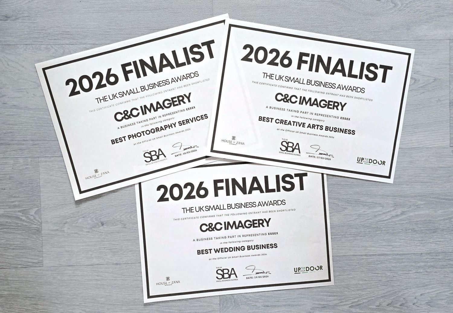 Multiple white rectangular finalist award certificates with black text and borders arranged on a gray textured surface.