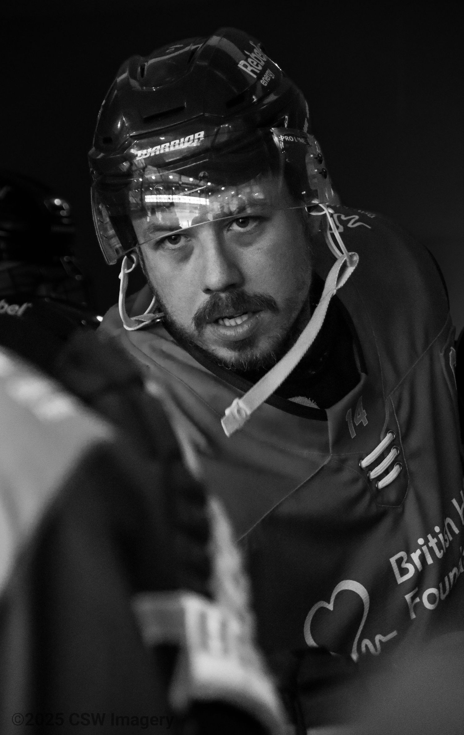 Black and white portrait of hockey player wearing helmet and protective gear.