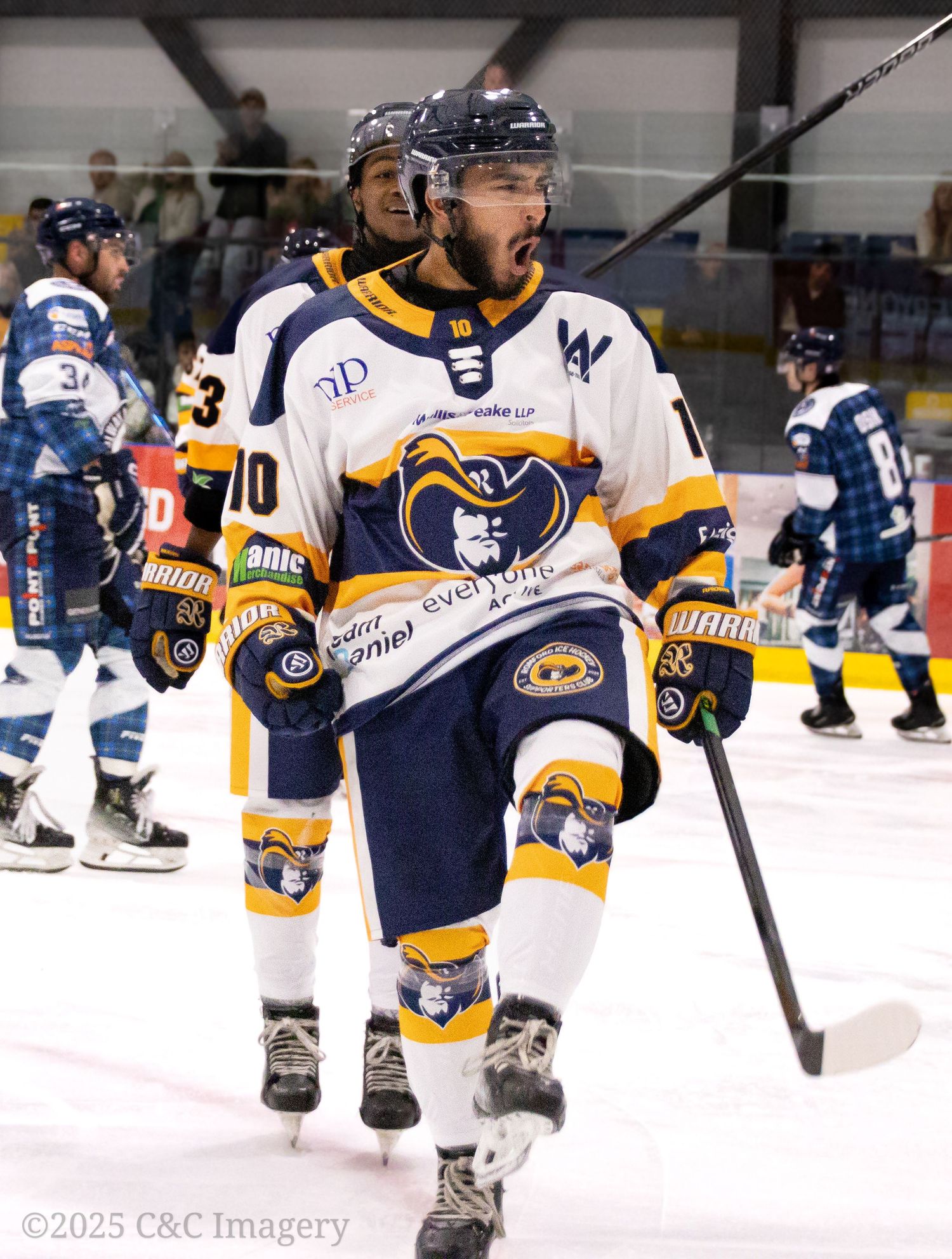 Hockey player in navy and yellow uniform stands ready on ice during match.