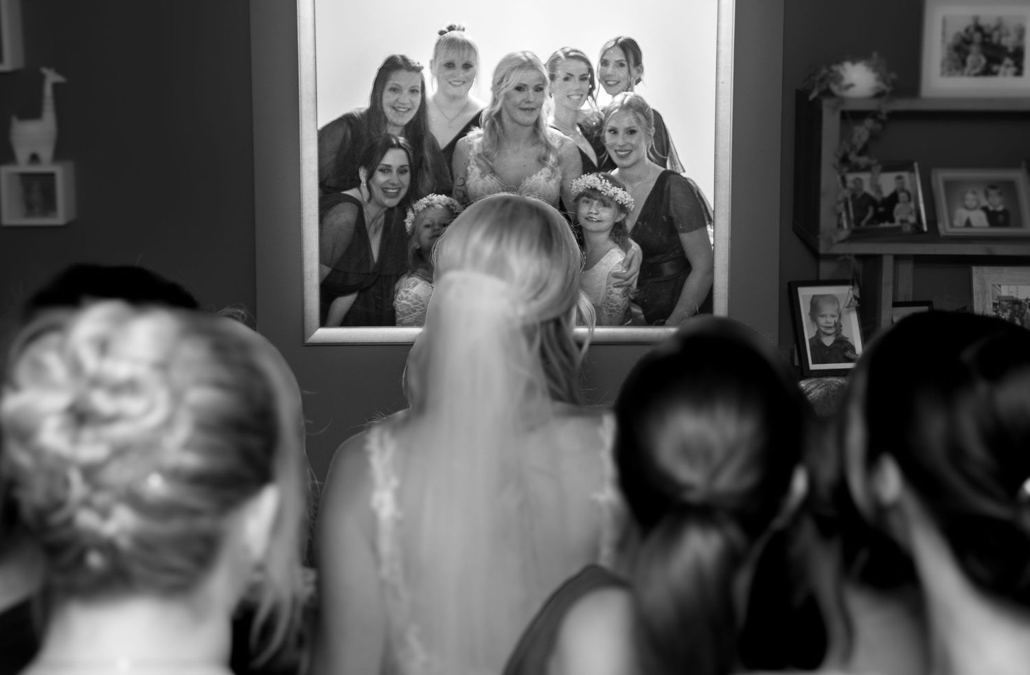 Black and white photo showing a series of framed pictures on a wall.