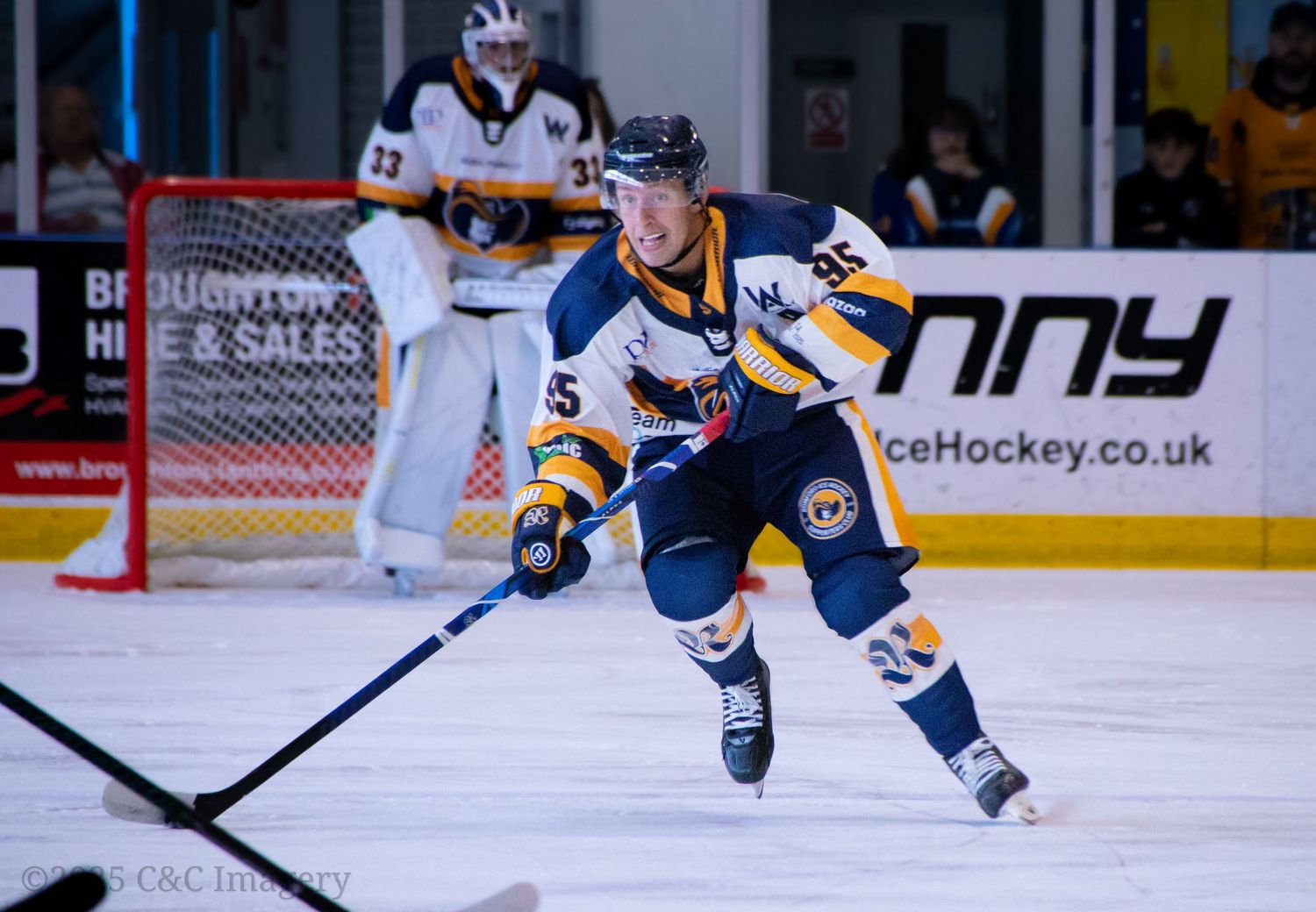 Ice hockey players in action during a competitive match with blue and orange jerseys.
