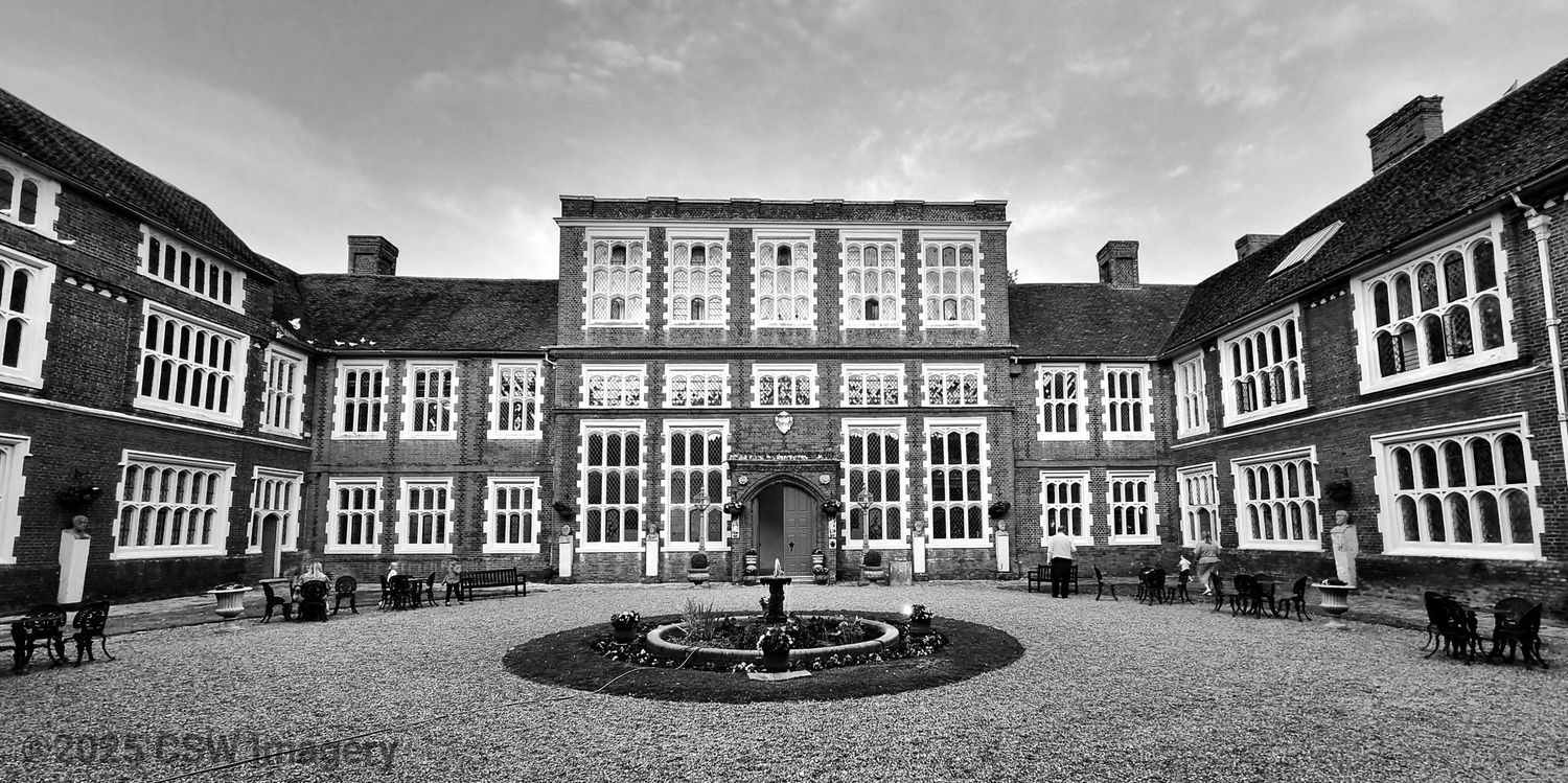 Wide angle panoramic view of a traditional brick school building with courtyard.