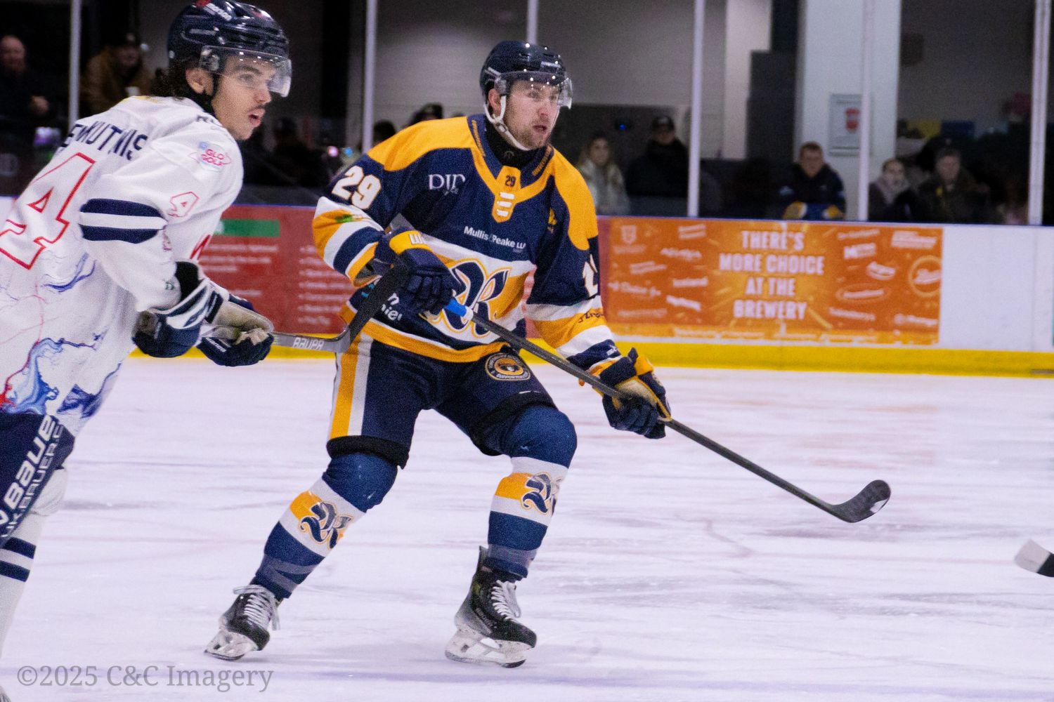 Ice hockey players in blue and white jerseys compete for the puck during a game.