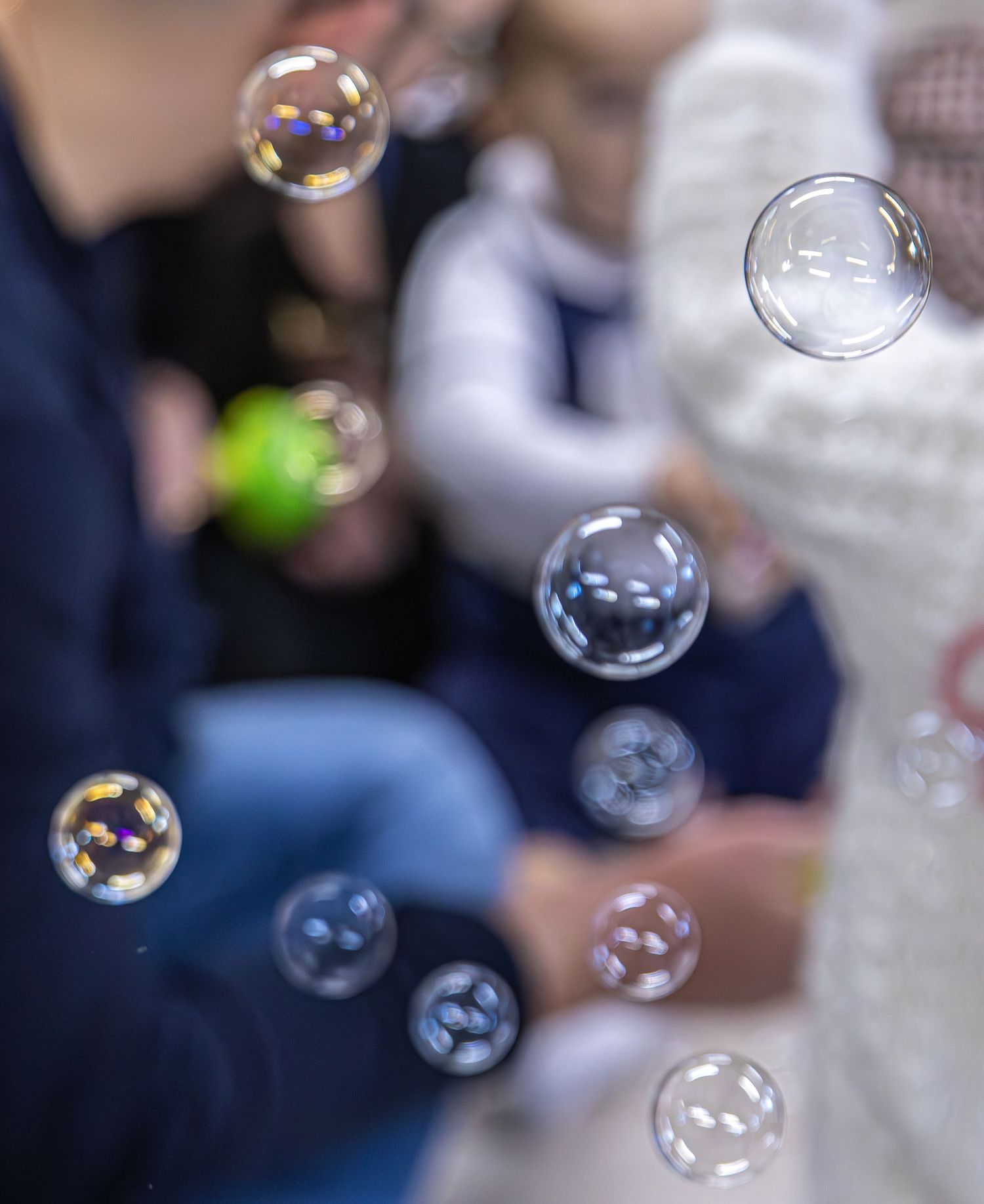 Colorful soap bubbles float in the air at a wedding celebration with blurred guests in the background.