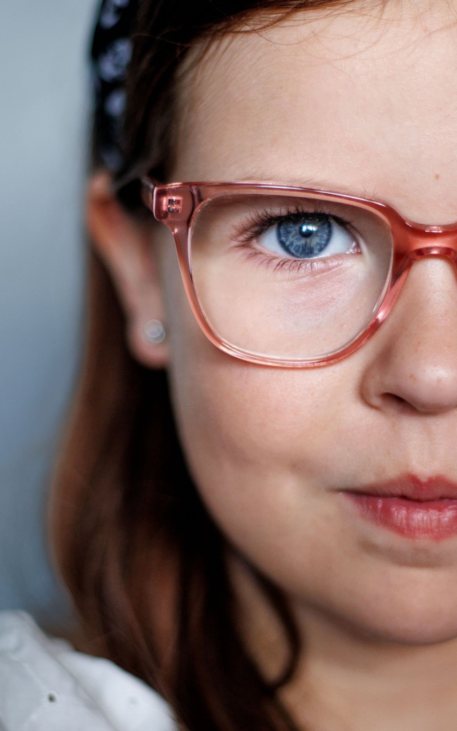 Close-up view of peach-colored eyeglasses frames and blue eye.