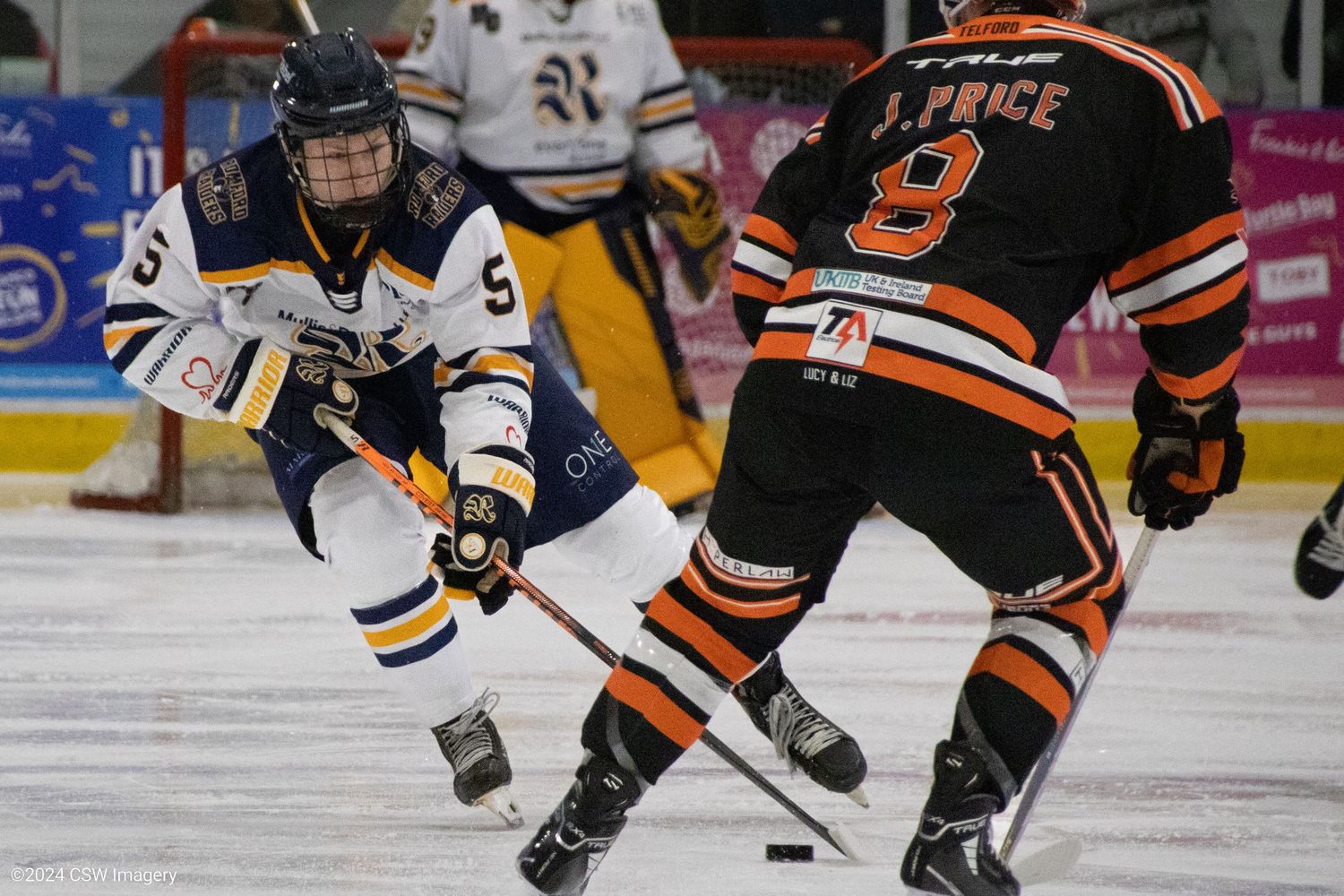 Hockey players in orange and black jerseys competing for the puck during an intense game.