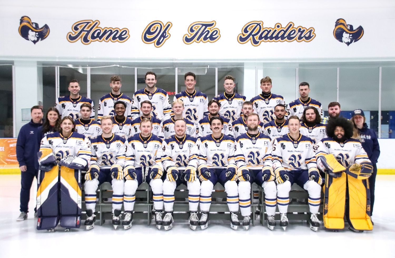 Panoramic team photo of hockey players lined up on ice in white uniforms.