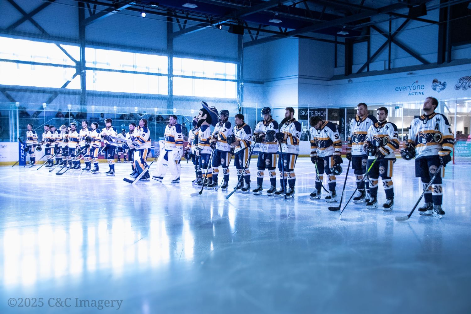 Hockey team lines up on ice rink during pre-game ceremony.