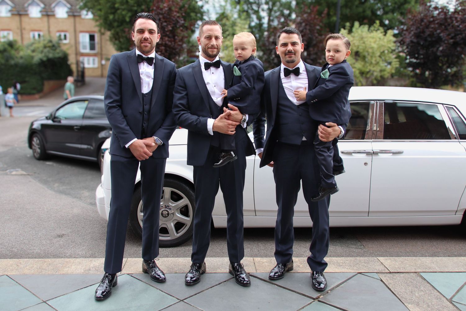 Groomsmen in formal attire pose playfully showing off their colorful socks.