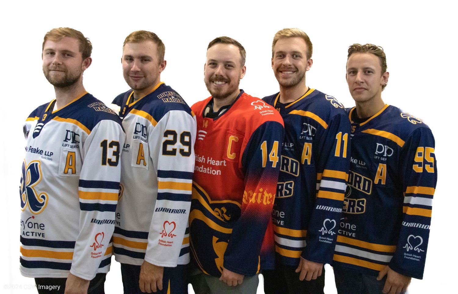Hockey players lined up in jerseys for team photo on ice rink.