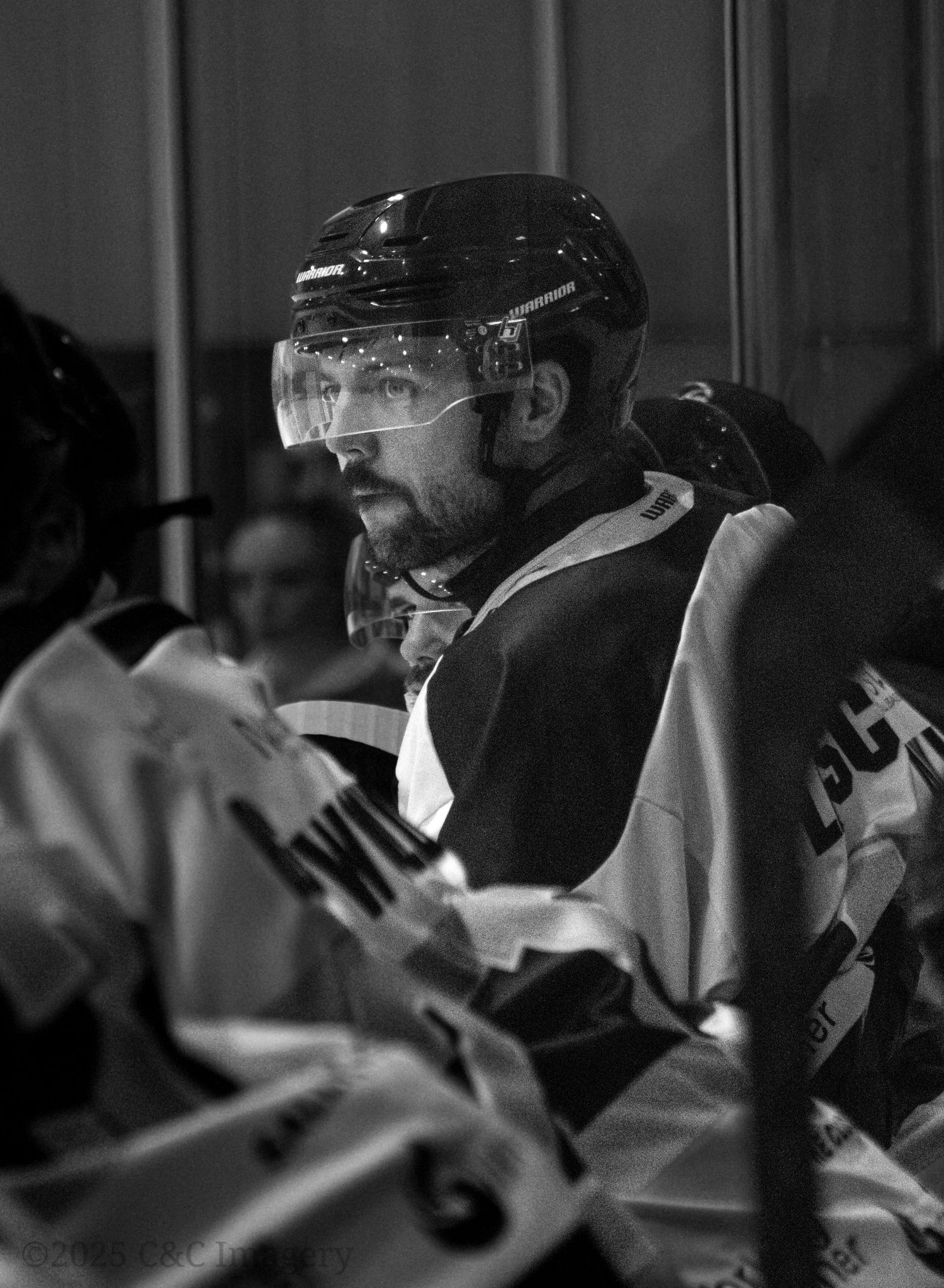 Close-up of hockey player on bench wearing protective visor and helmet.
