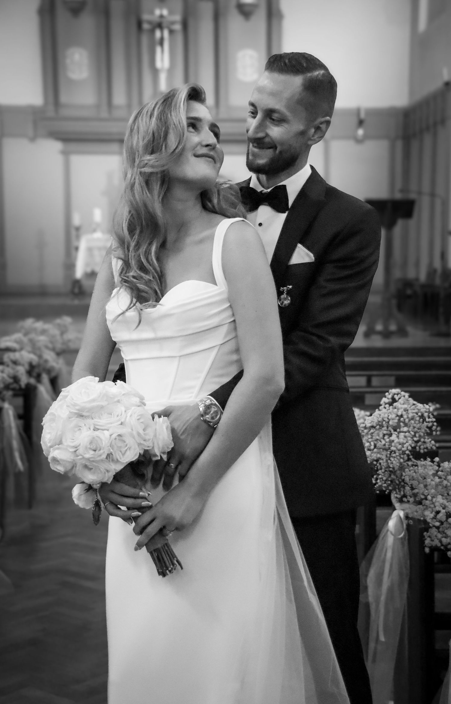 Black and white portrait of newlyweds sharing an intimate moment with white bouquet.