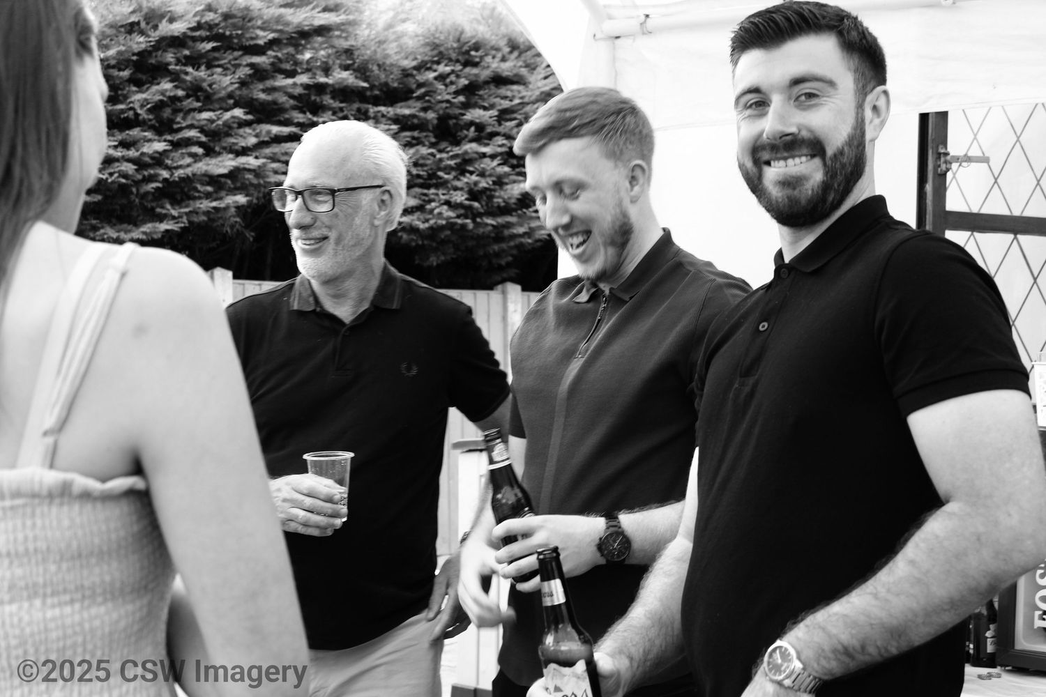 Group of men having drinks and conversation at an outdoor social event.