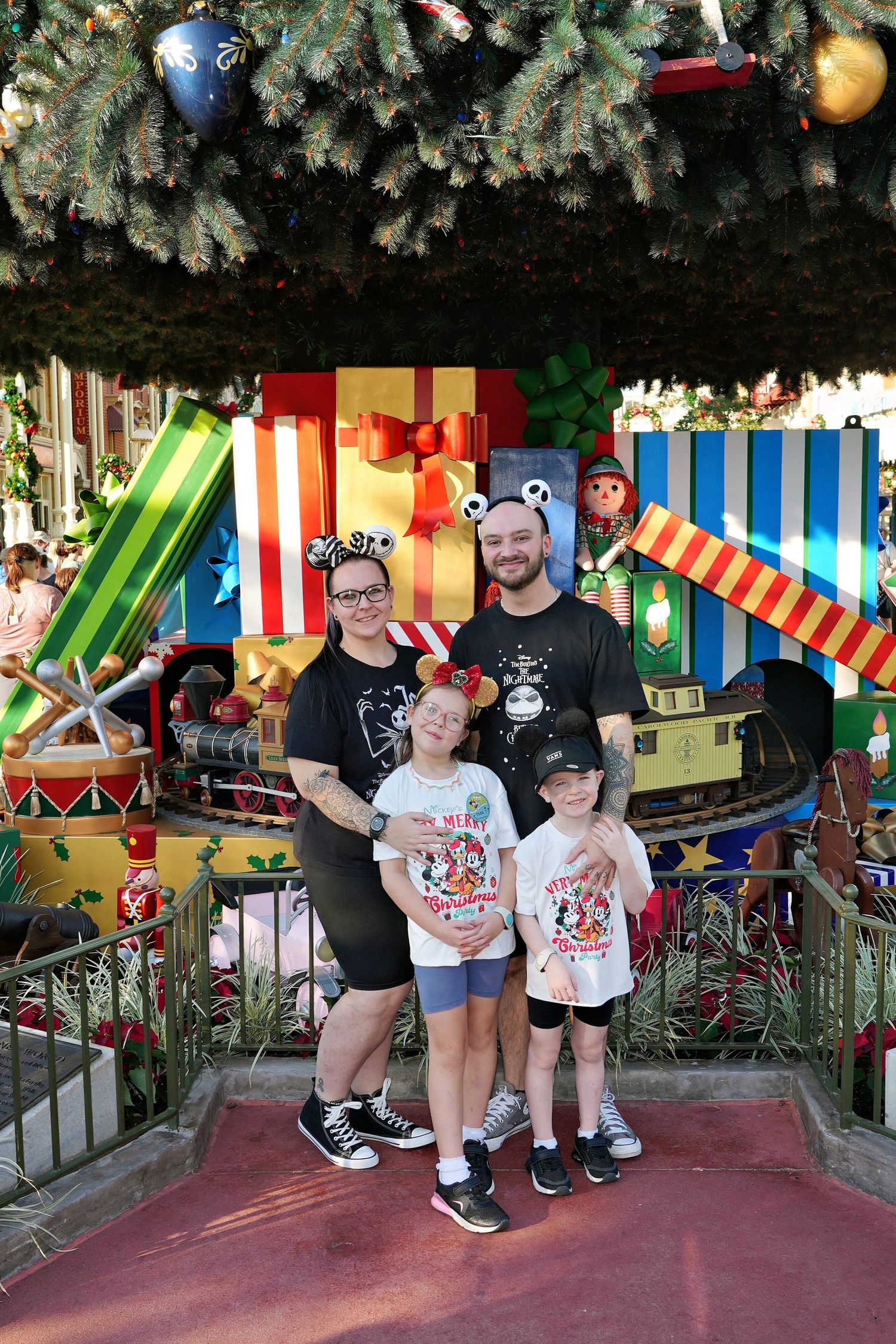 A group photo under decorated Christmas trees with colorful striped decorations.