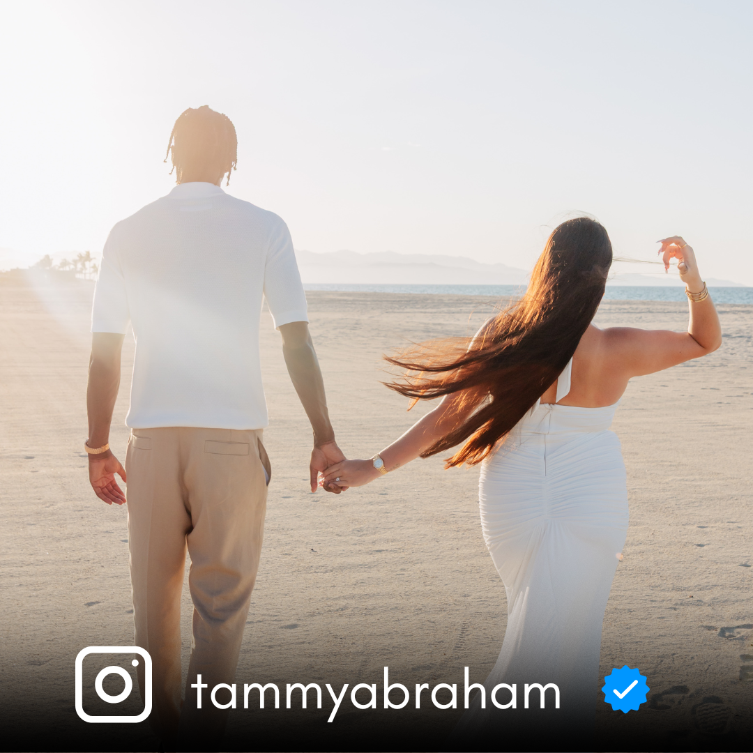 Couple walking hand in hand on a beach at sunset.