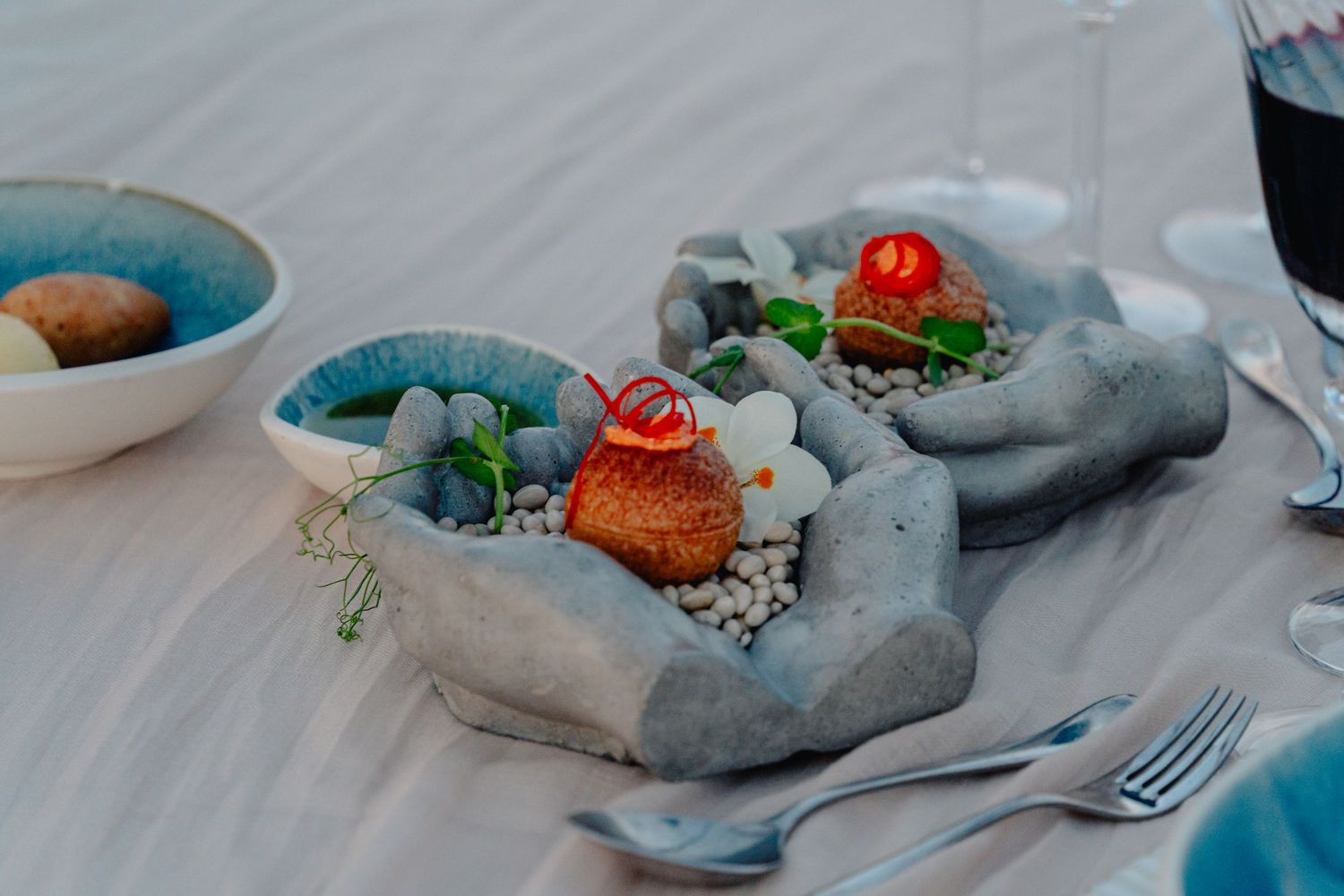 Modern table setting with gray napkins and colorful floral accents on white linens.
